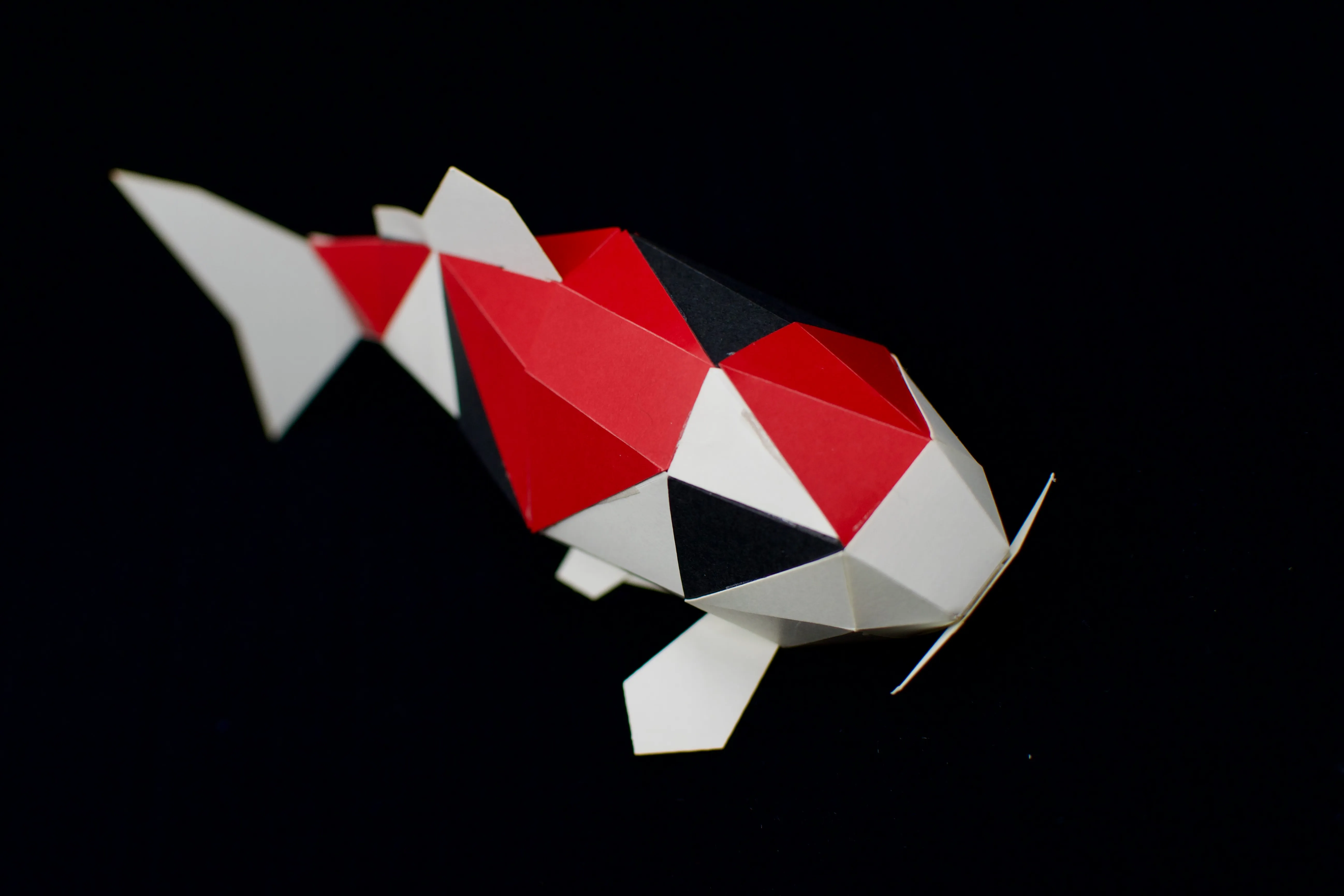 A papercraft koi made with white, red, and black paper