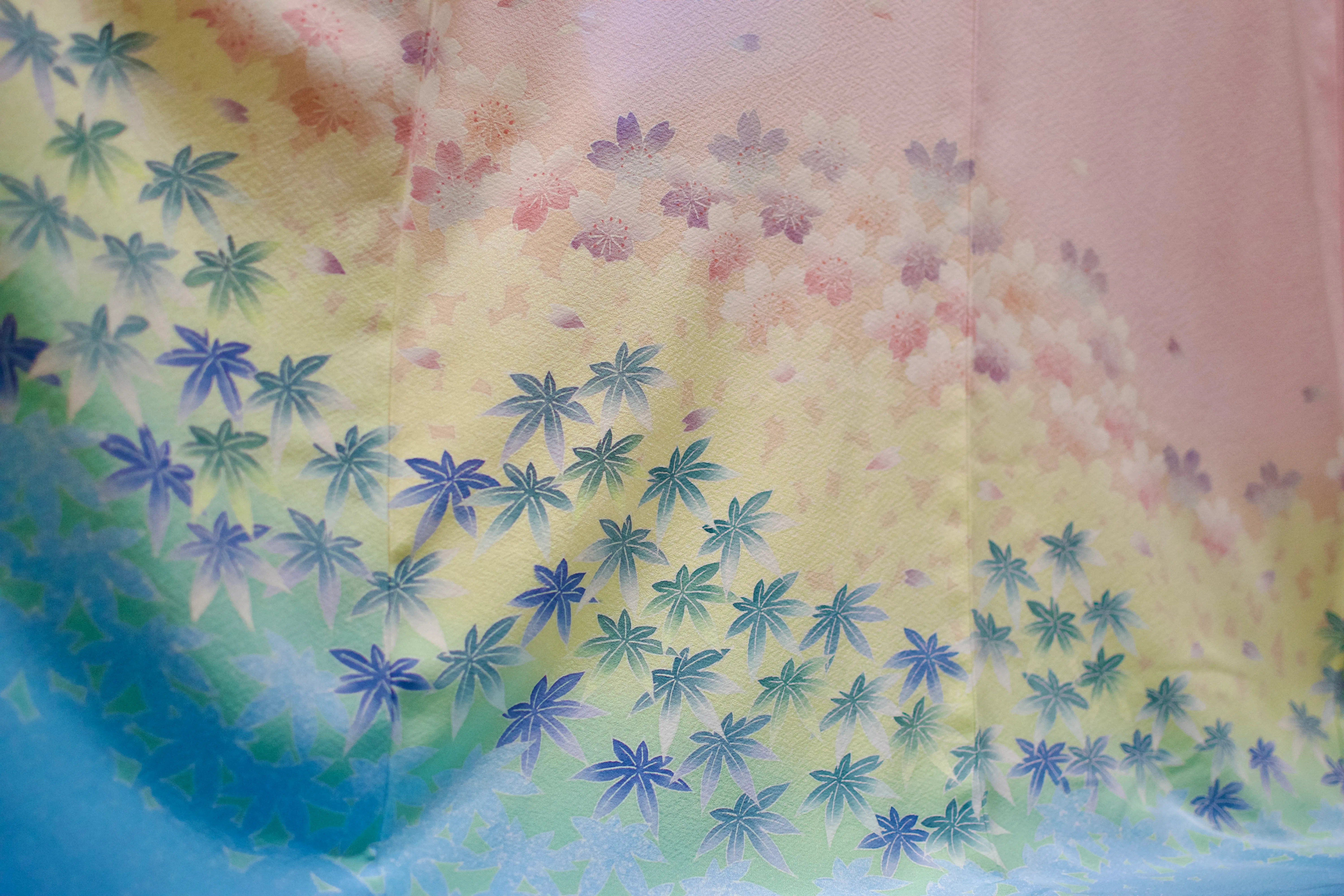 A kimono with a pastel rainbow pattern covered in leaves