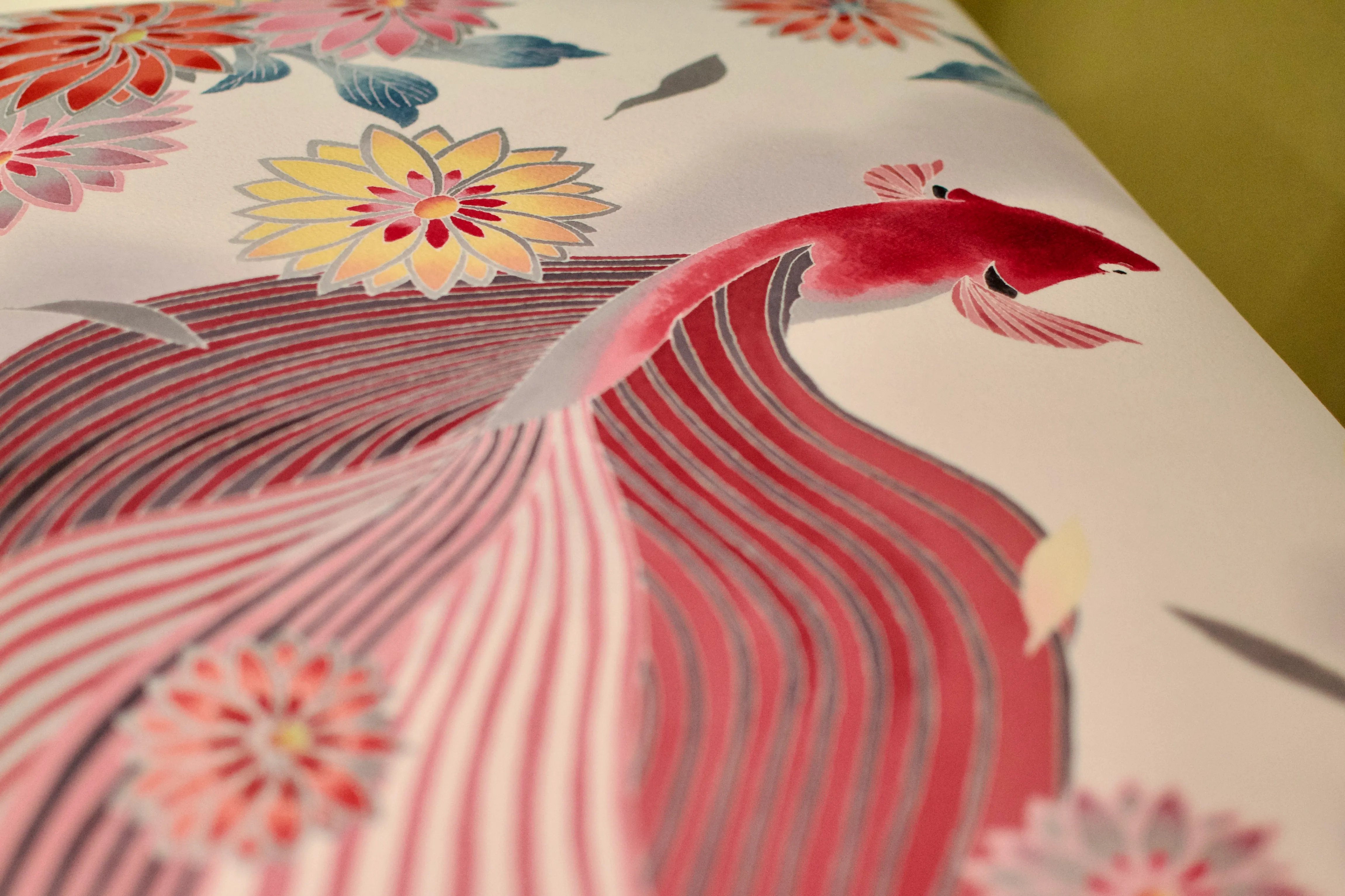 A bench cover dyed with a pattern of flowers and a large pink koi fish with flowing tail fins