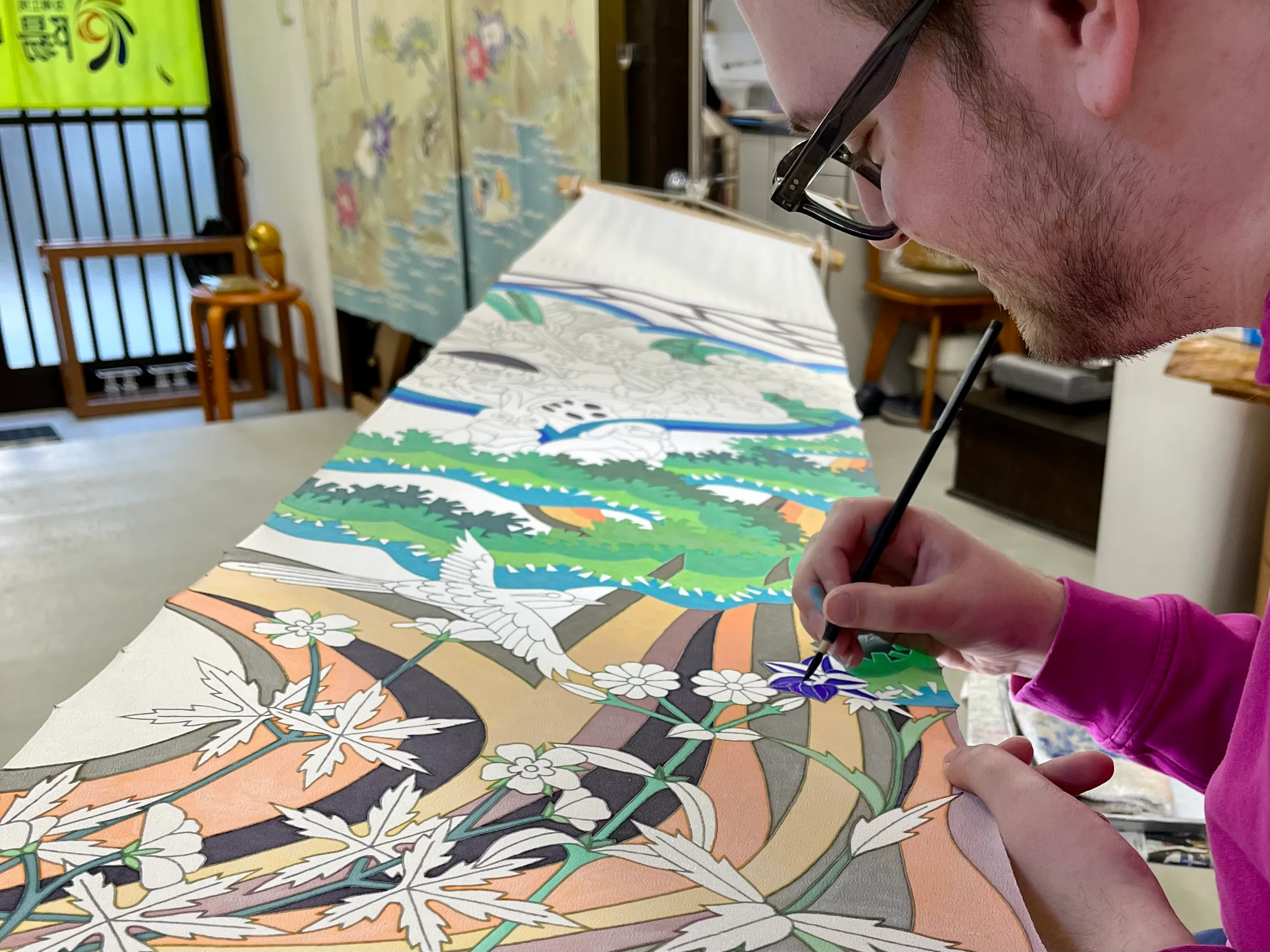Ross paints a flower on a large banner
