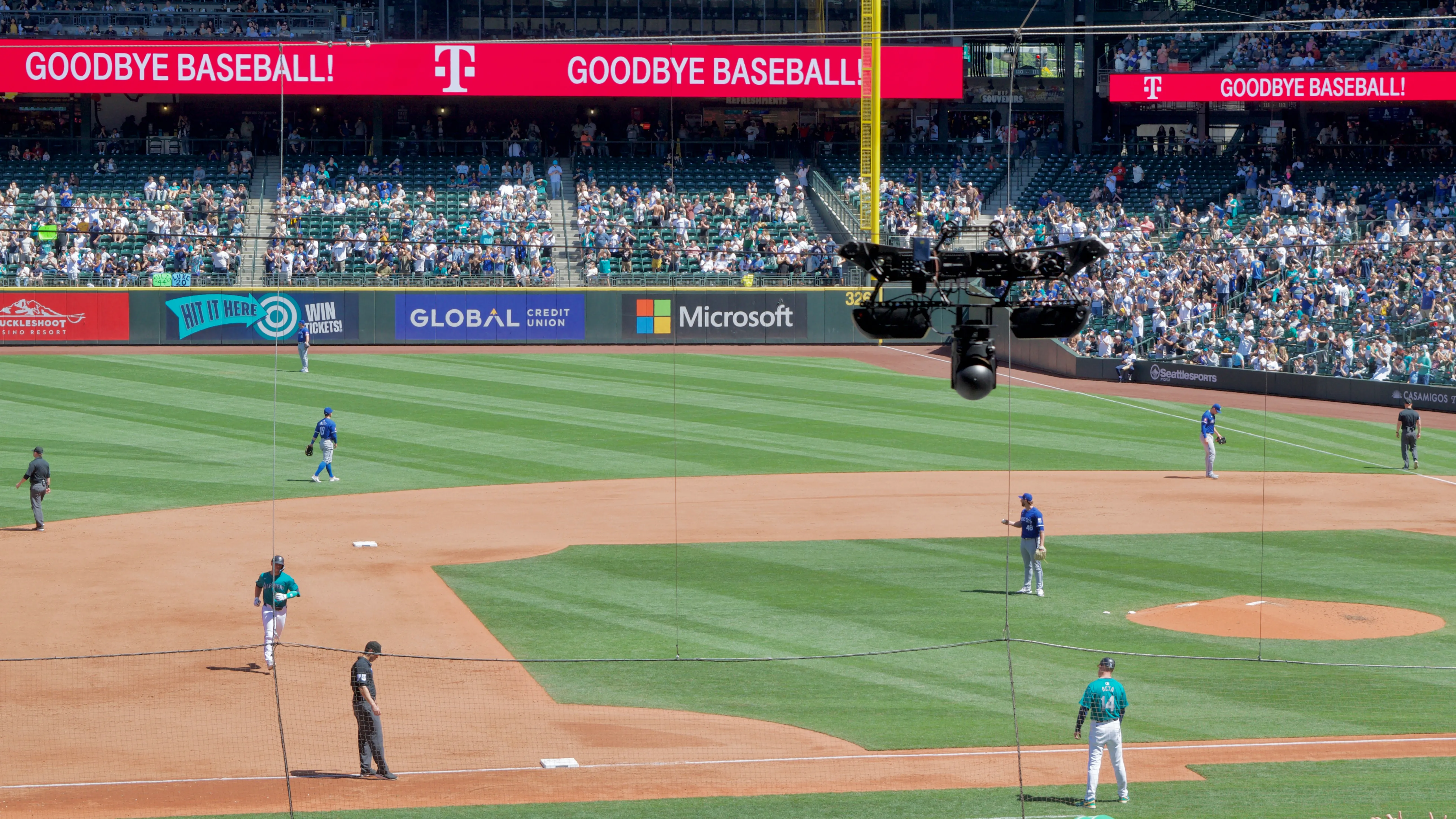 A mobile camera hanging from a pair of cables follows a Seattle Mariners baseball player jogging towards third base