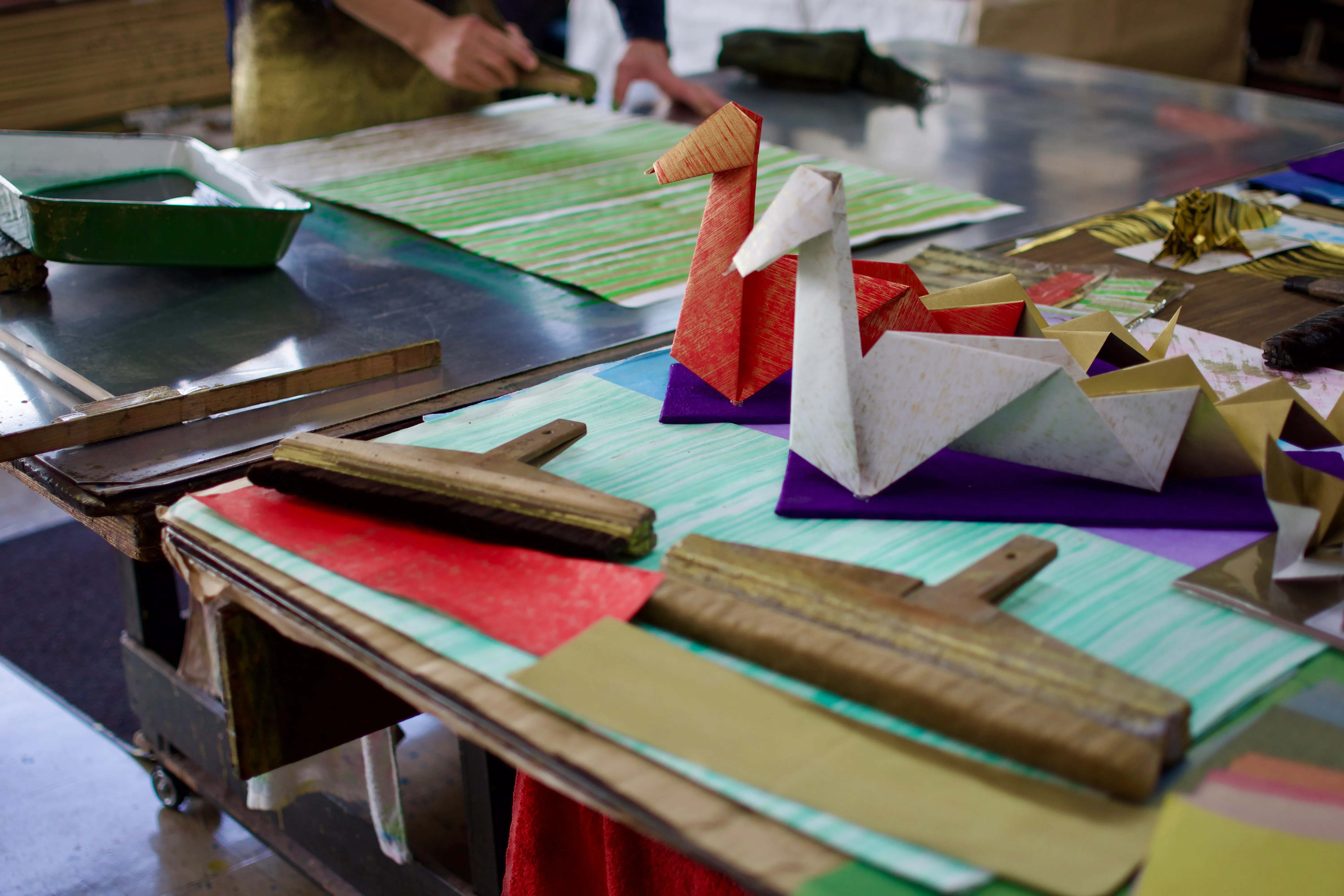 Large origami snakes and brushes displayed in front of a paper craftsman’s work table