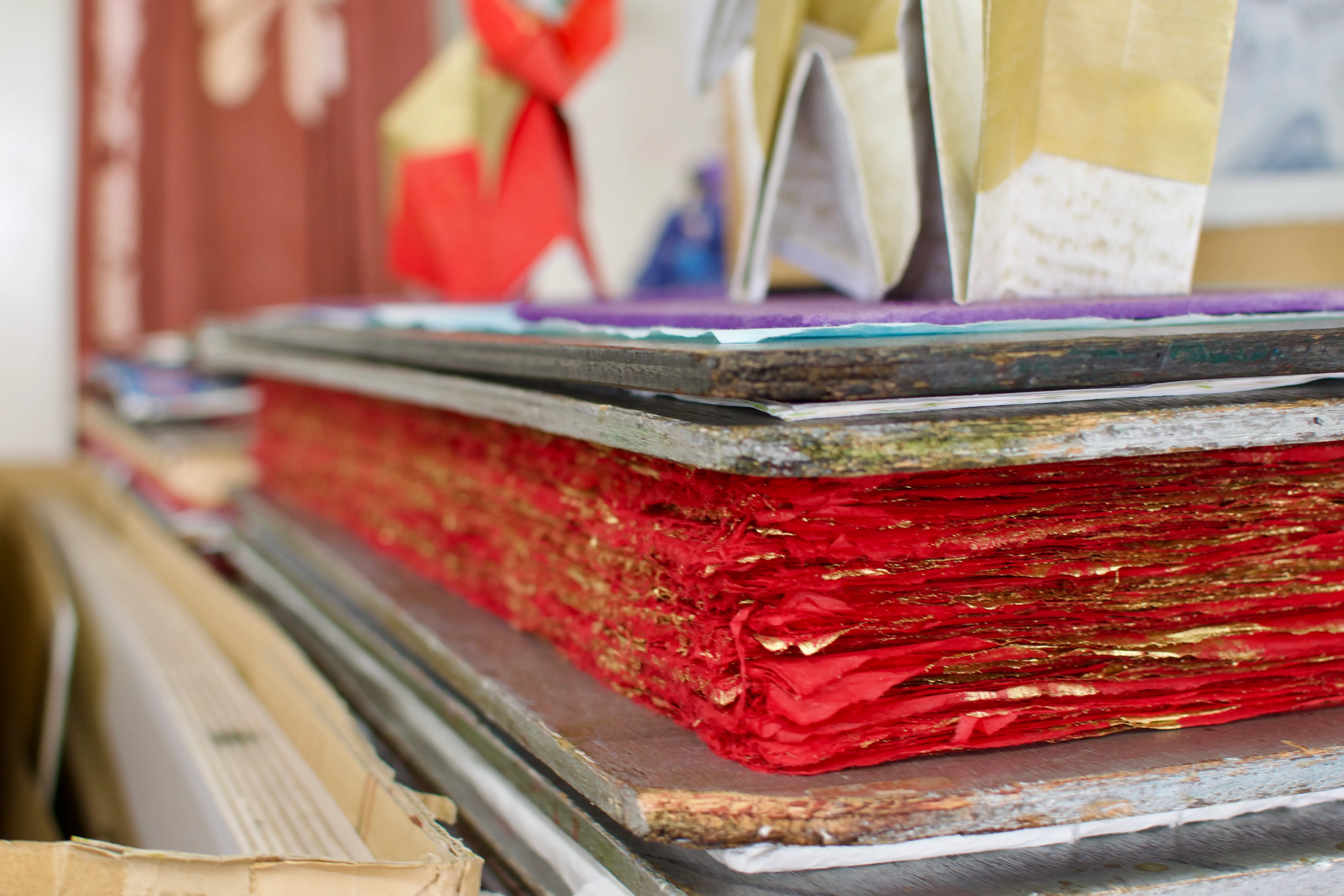 A stack of dyed washi paper is flattened and compressed