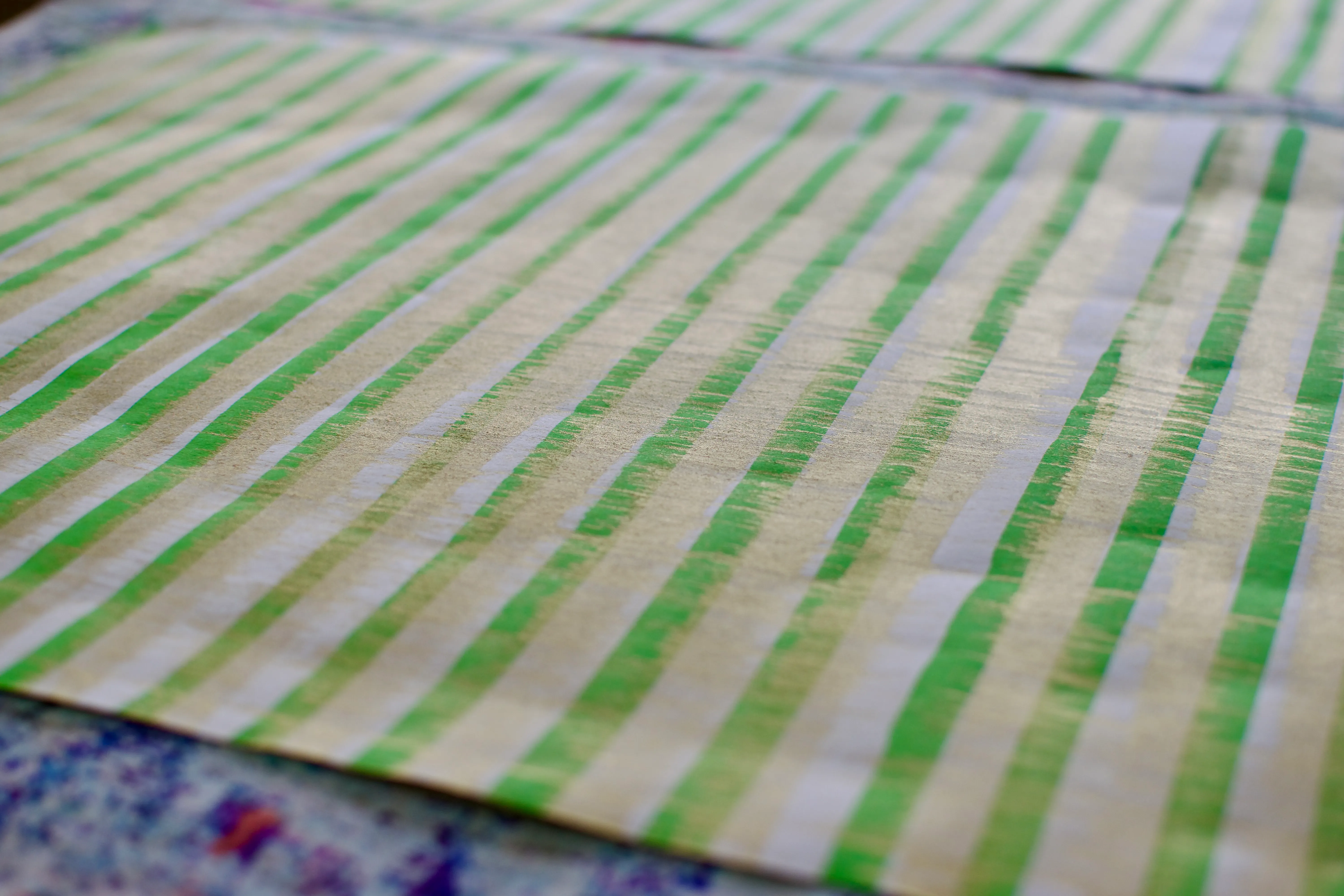 A large sheet of white paper with newly-painted green and gold stripes