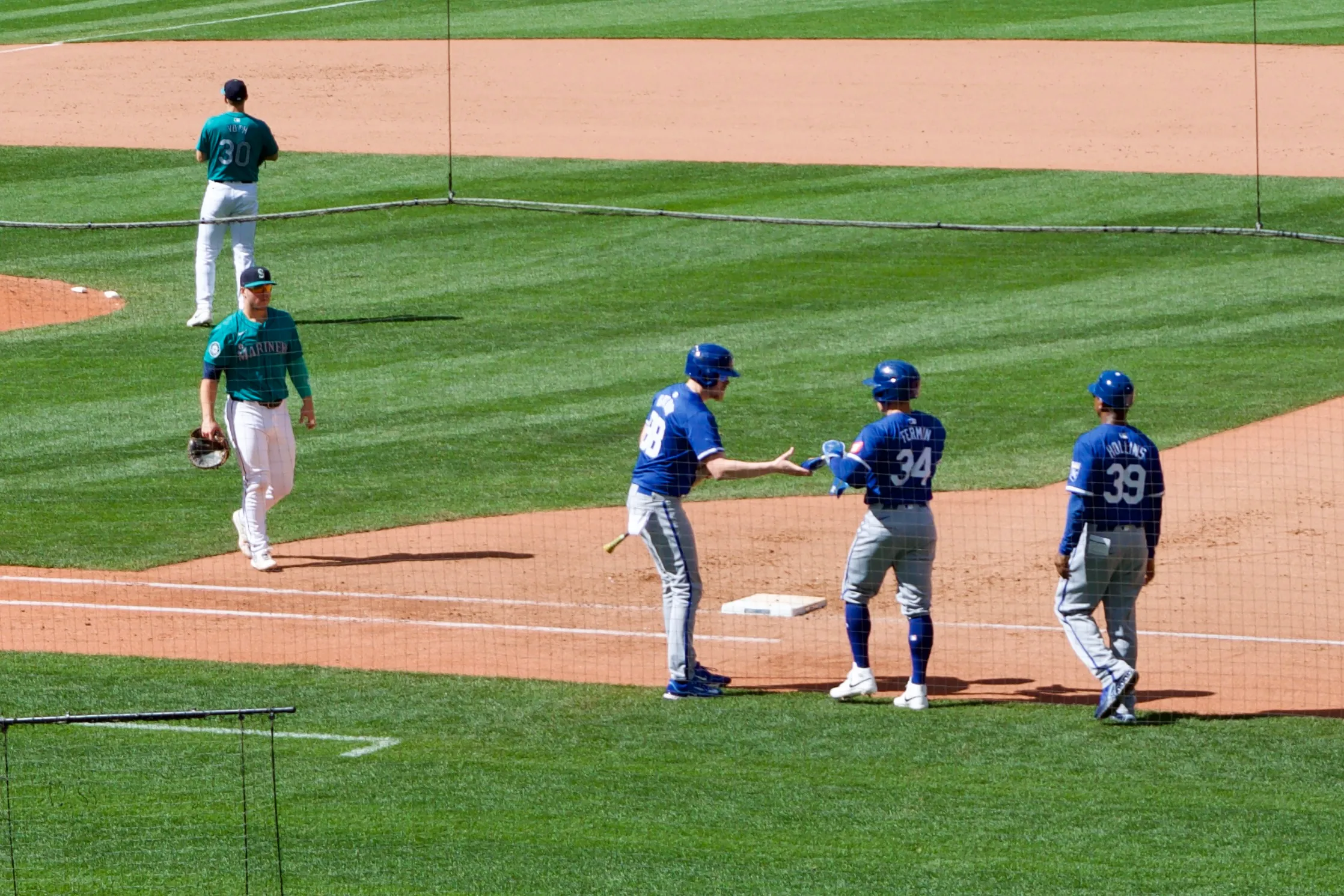 The Kansas City Royals' Freddy Fermin hands his batting gloves to his team's batboy