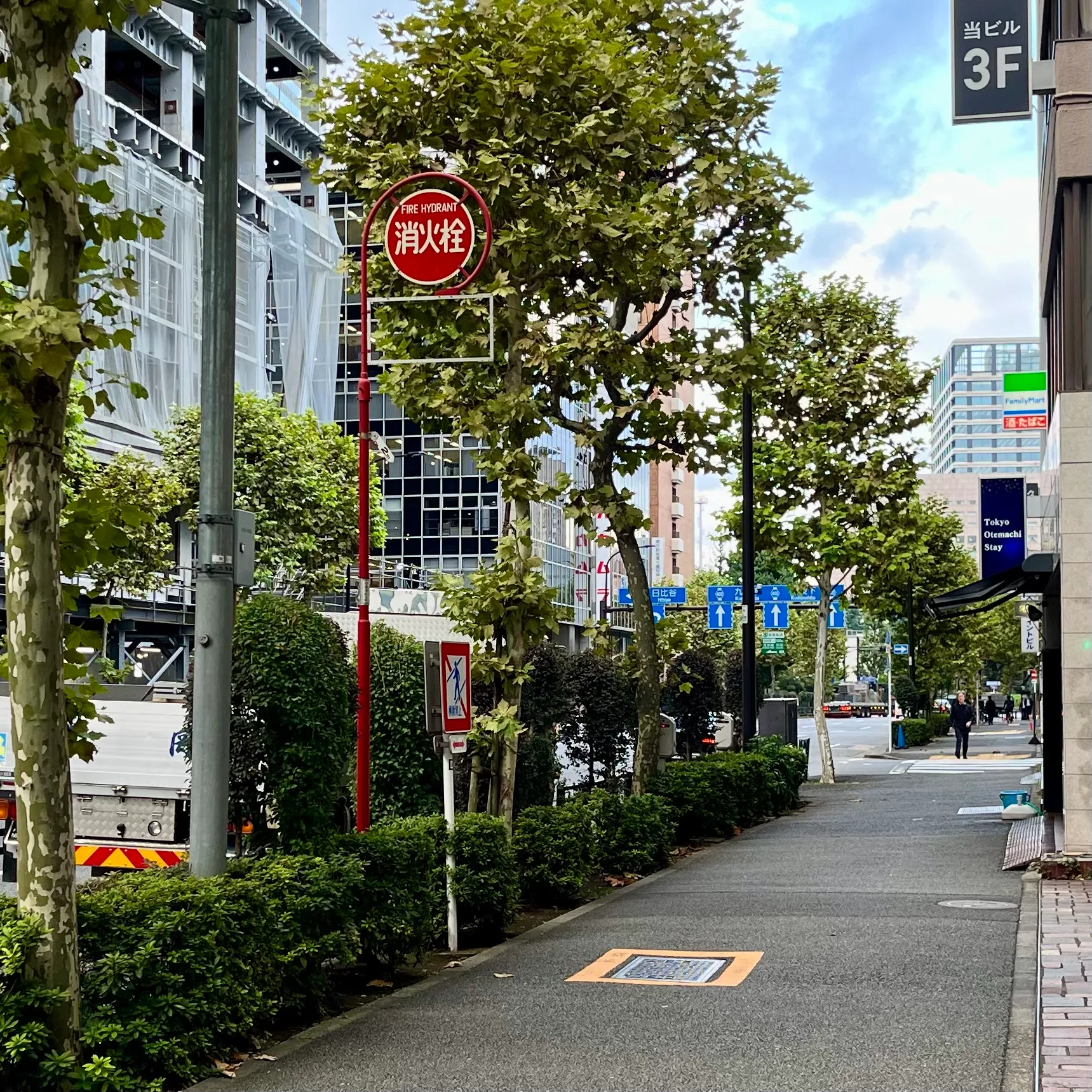 A Japanese fire hydrant sign next to a yellow-bordered manhole cover on the ground
