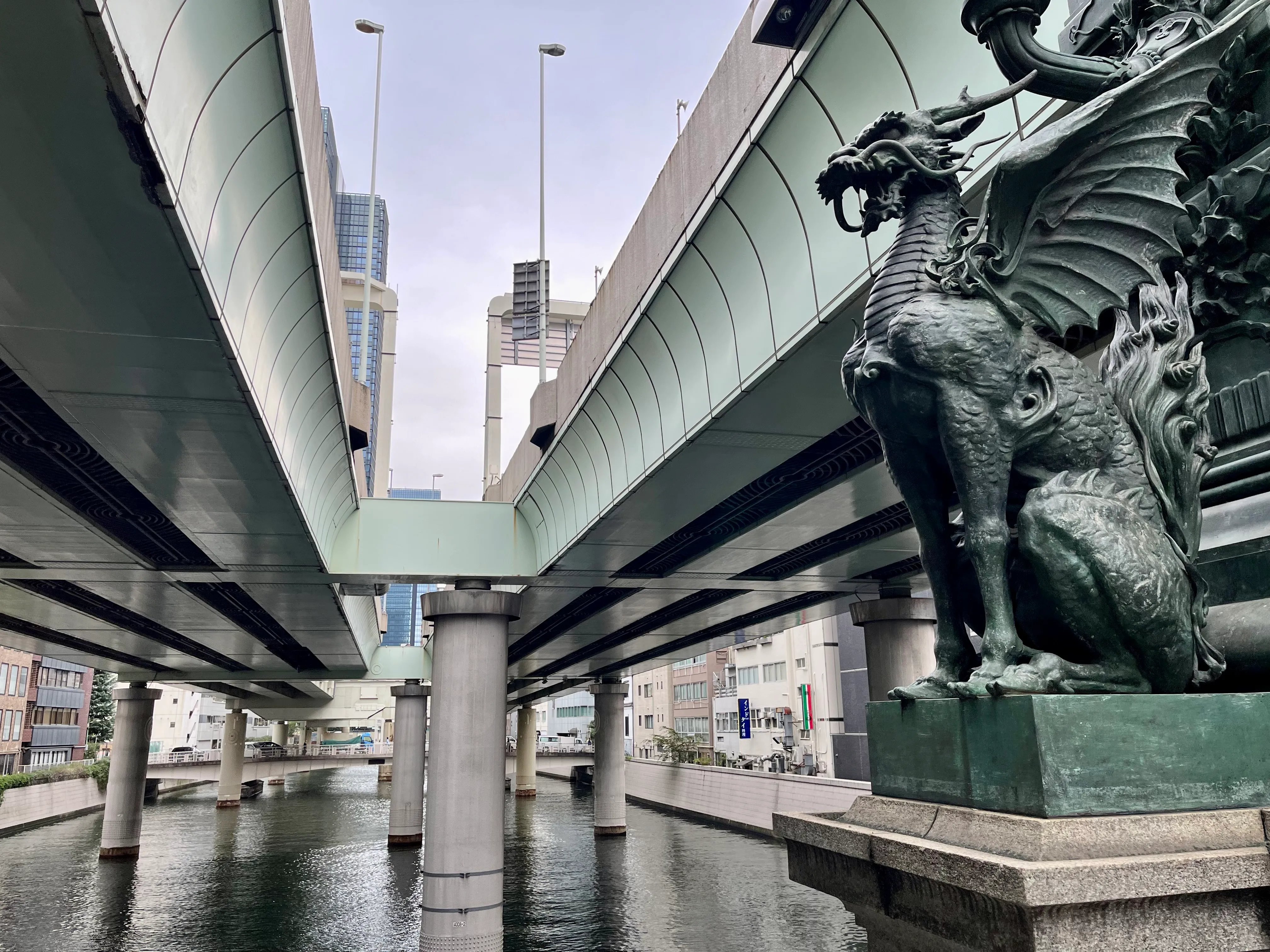 A dragon statue sits between two expressway bridges over a river
