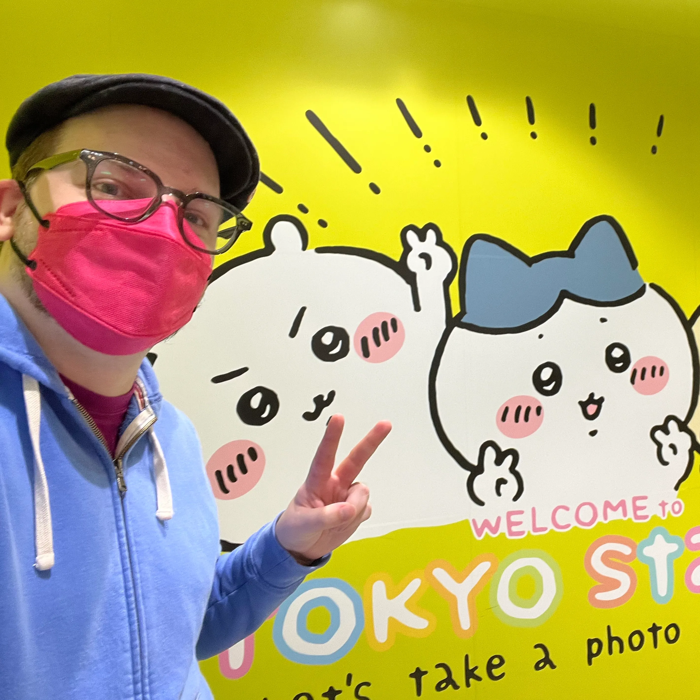 Ross posing in front of Chiikawa characters on a wall on Character Street