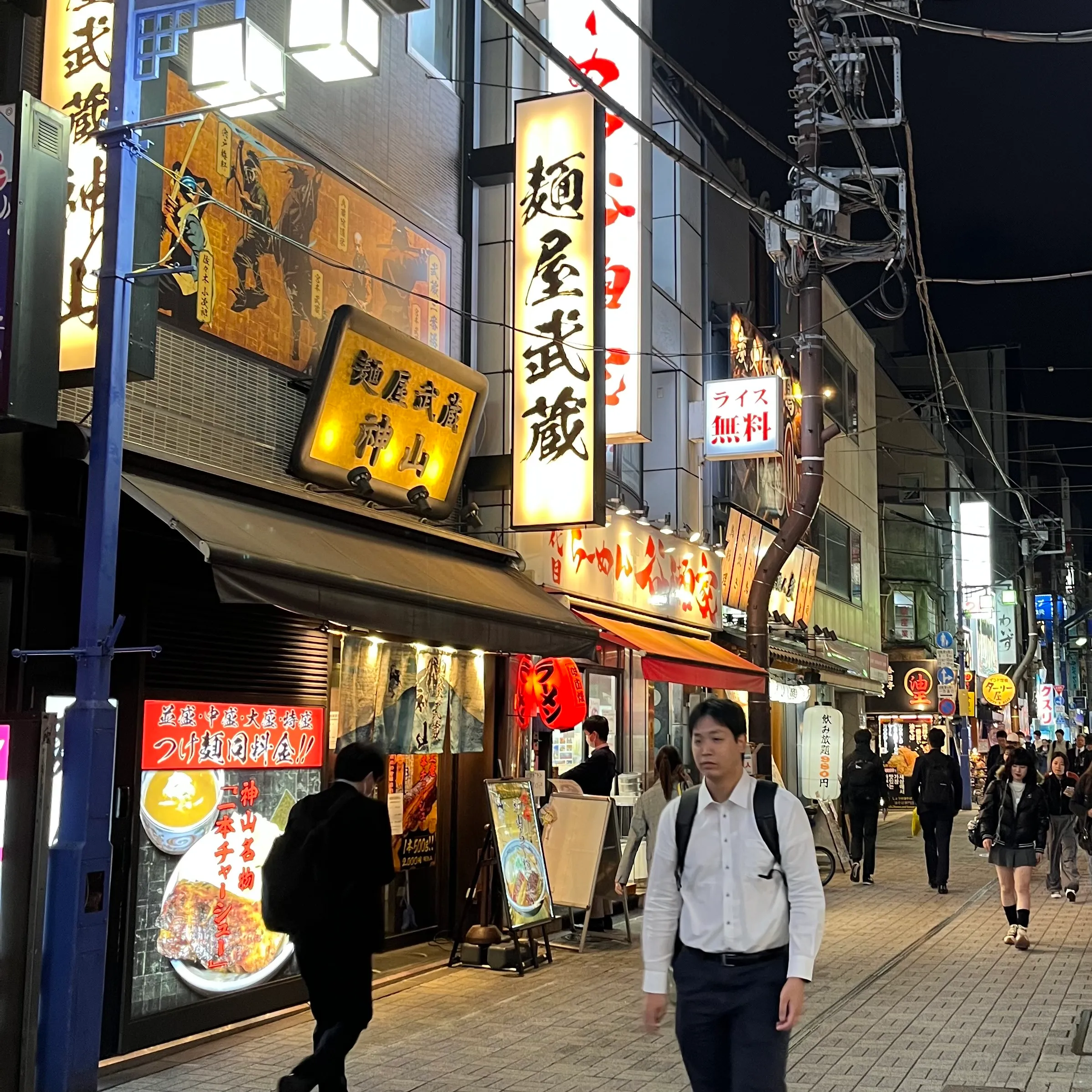Businessmen and students walk past restaurants near Kanda Station