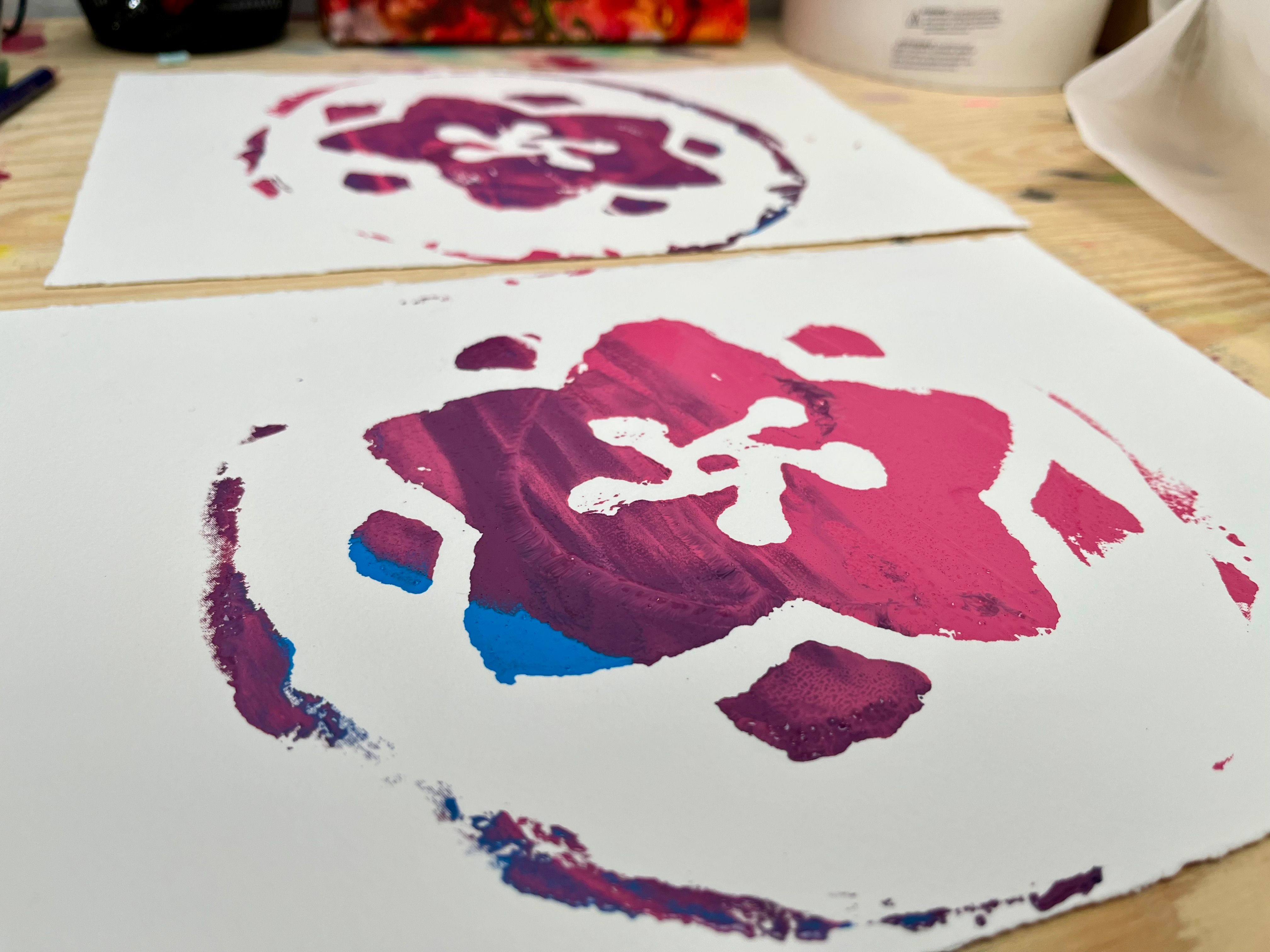 A pink, purple, and blue flower screen printed onto paper.