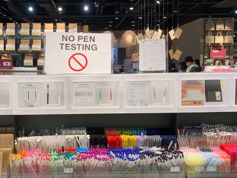 A sign reads 'No Pen Testing' in Muji's stationary section