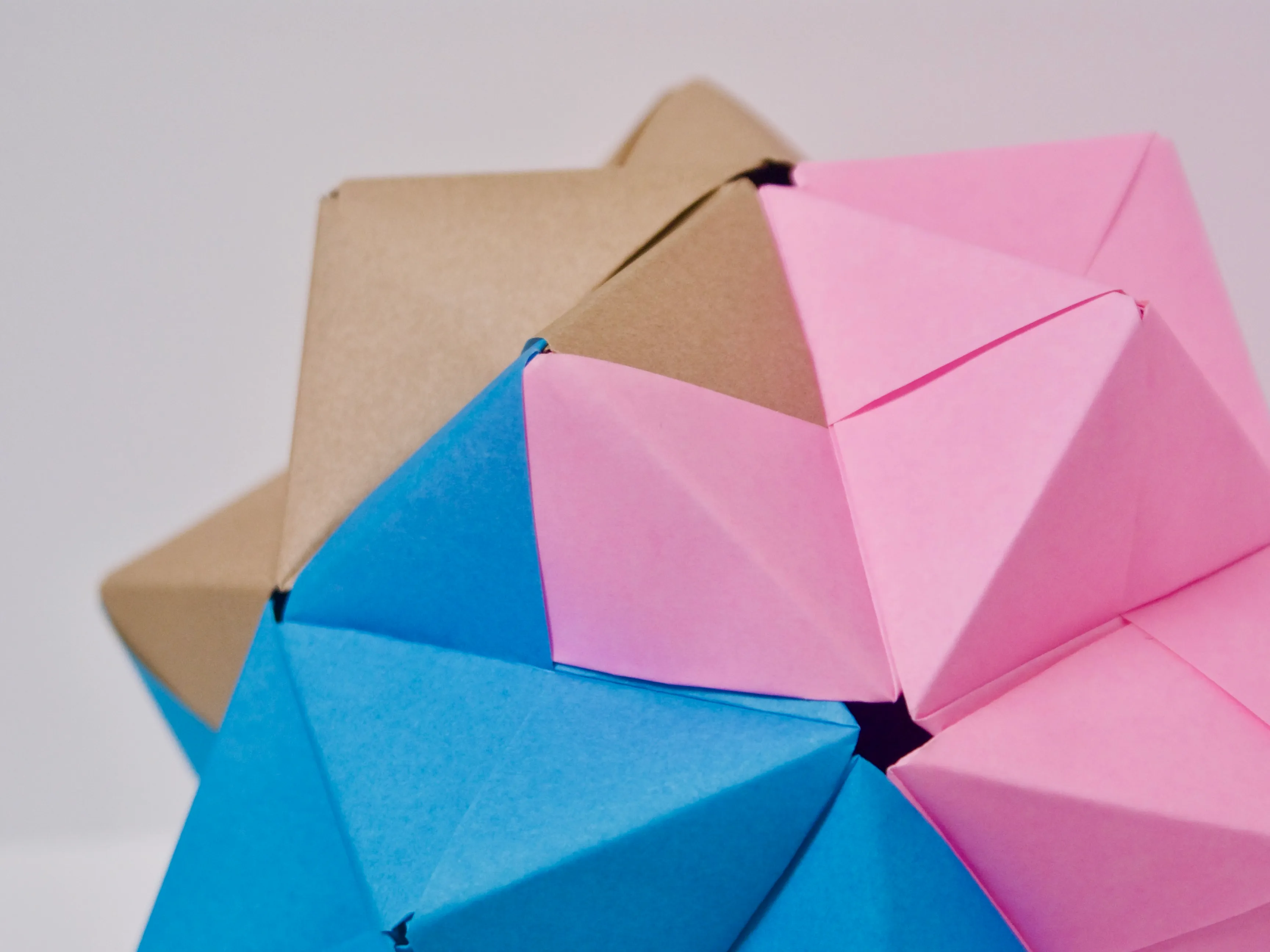 A spiky ball made from pink, brown, and blue origami paper