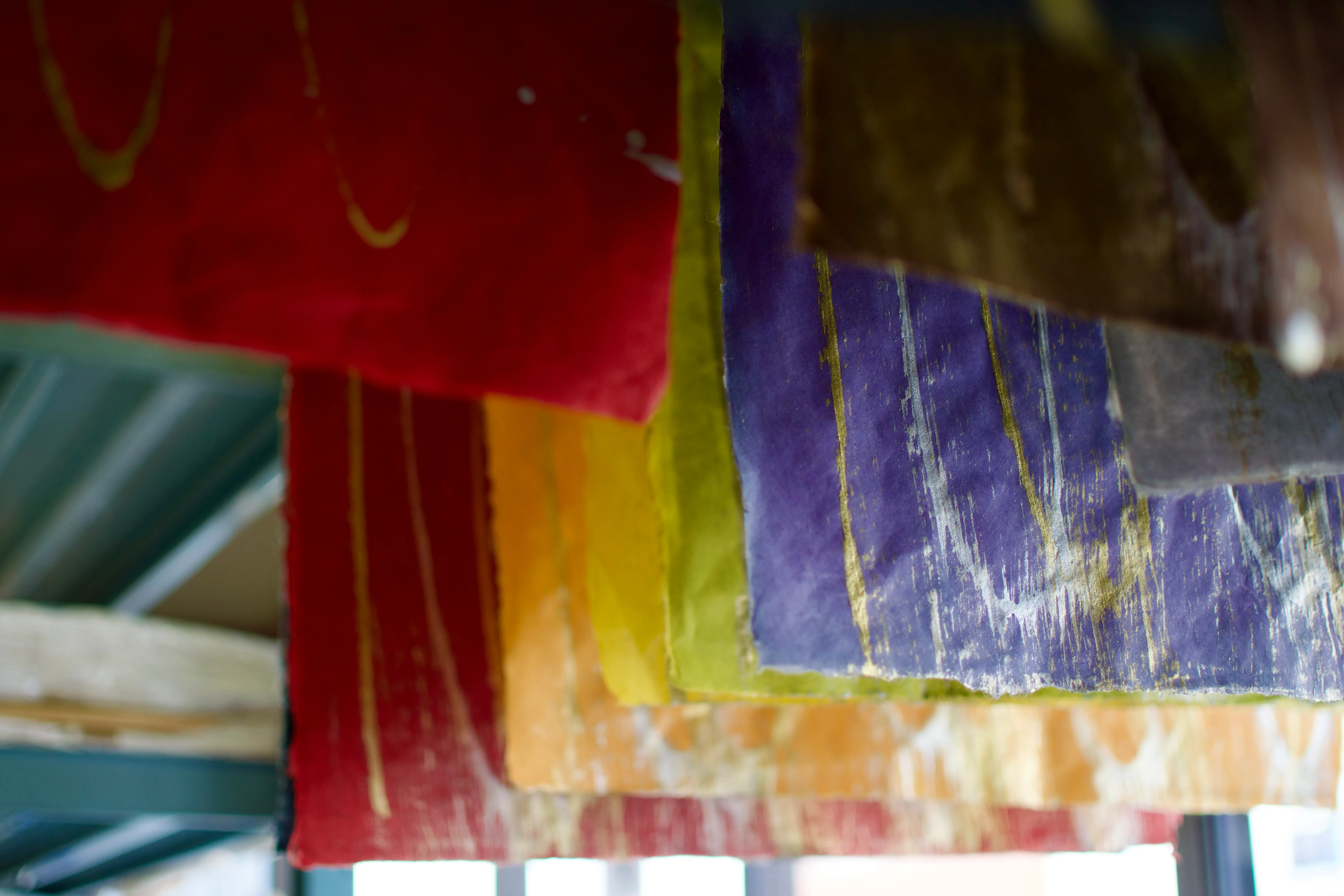 Freshly painted origami paper of various colours hang to dry