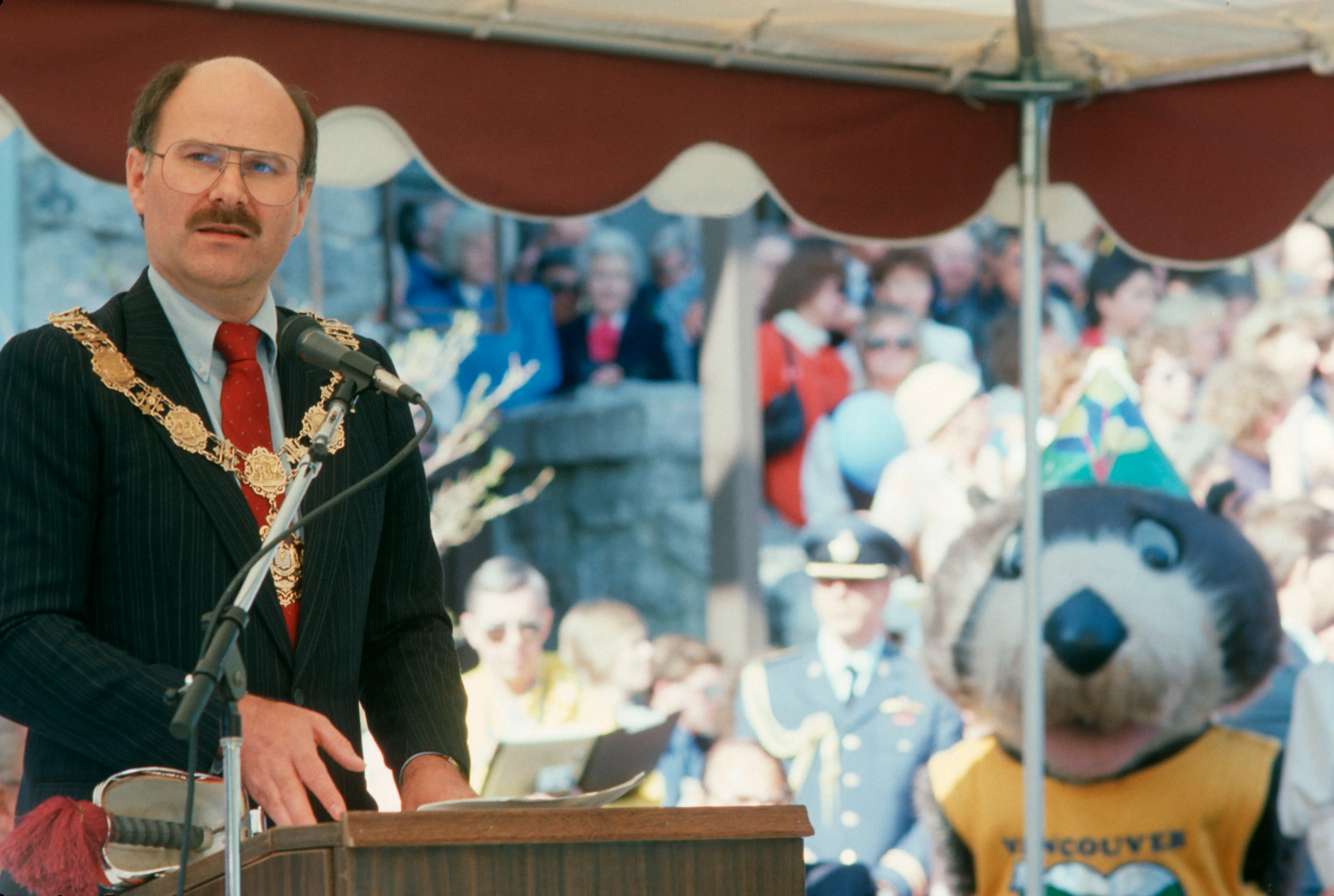 Mayor Harcourt delivering speech with Tillicum in background