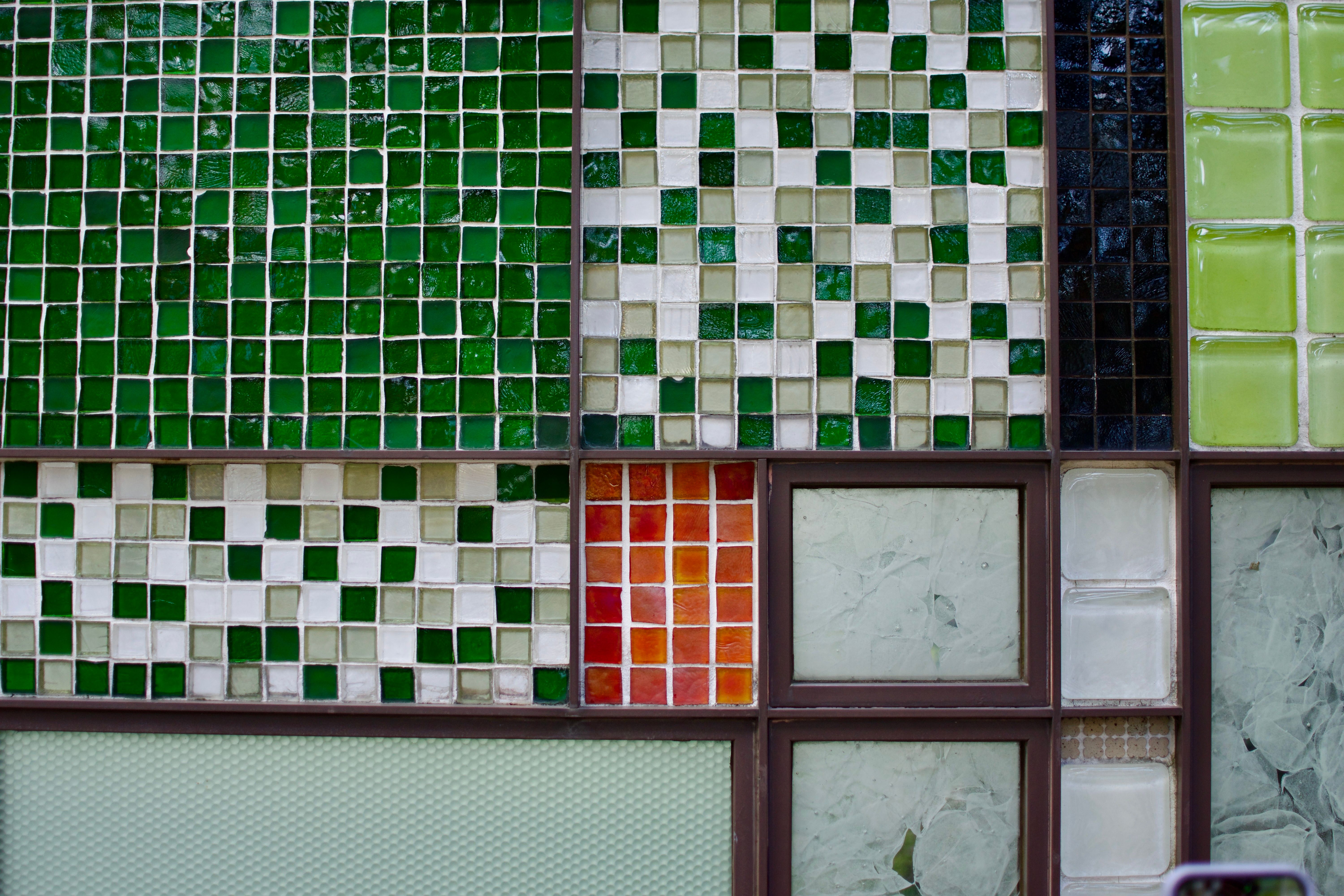 A tile mosaic featuring rectangular sections of different patterns. Some sections are built from green and white square tiles; others have interesting patterns in larger panes of partly-frosted glass.