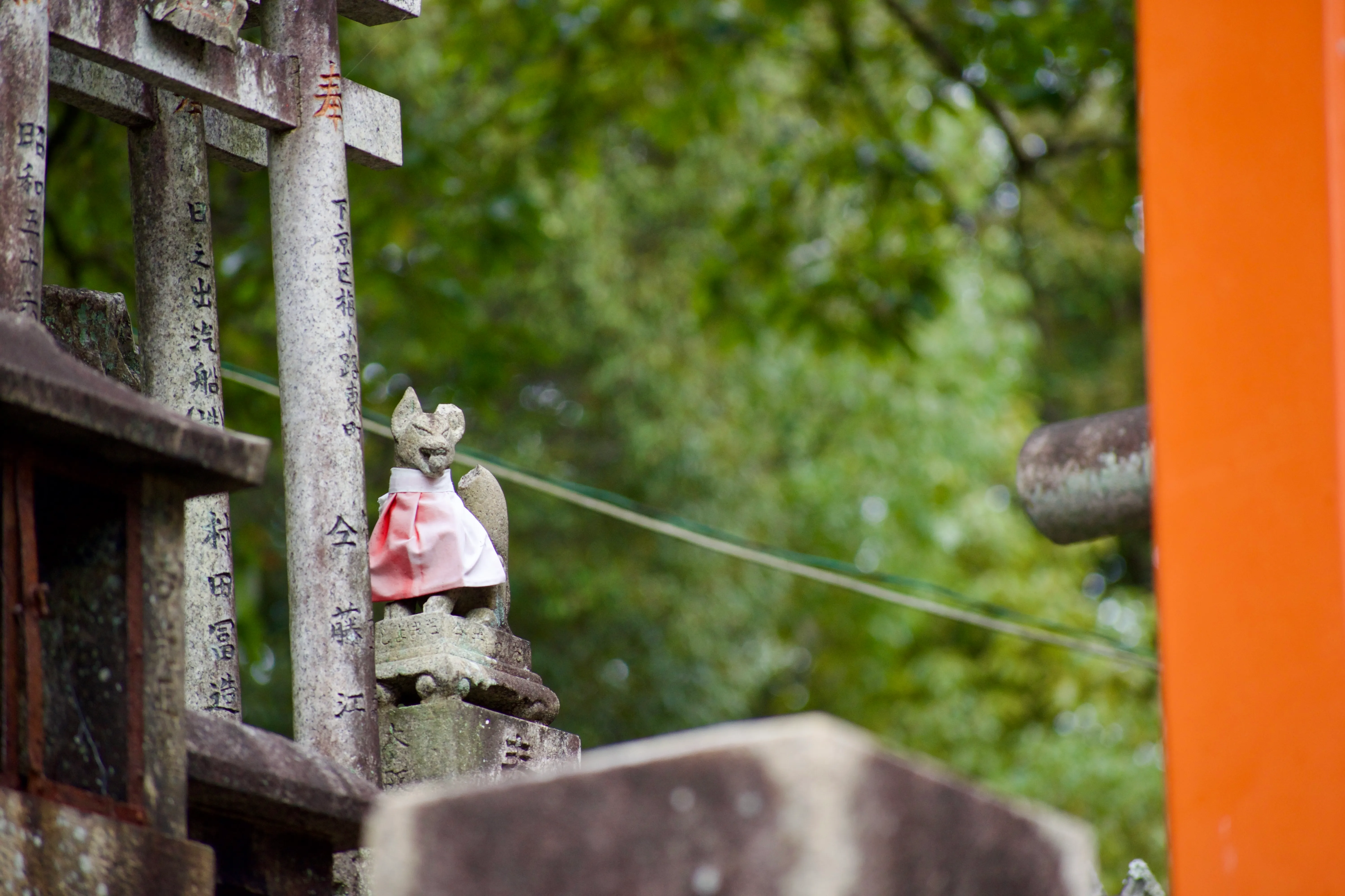 A small fox statue guarding a torii gate at Fushimi Inari Taisha