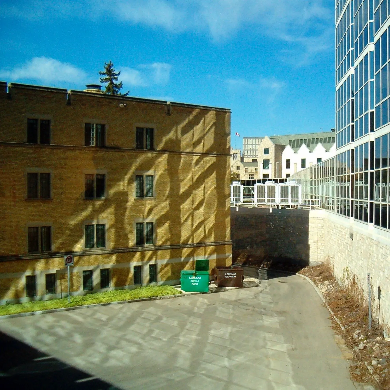 Light reflects off a modern glass building, projecting a diamond pattern on the brick wall of the facing building.