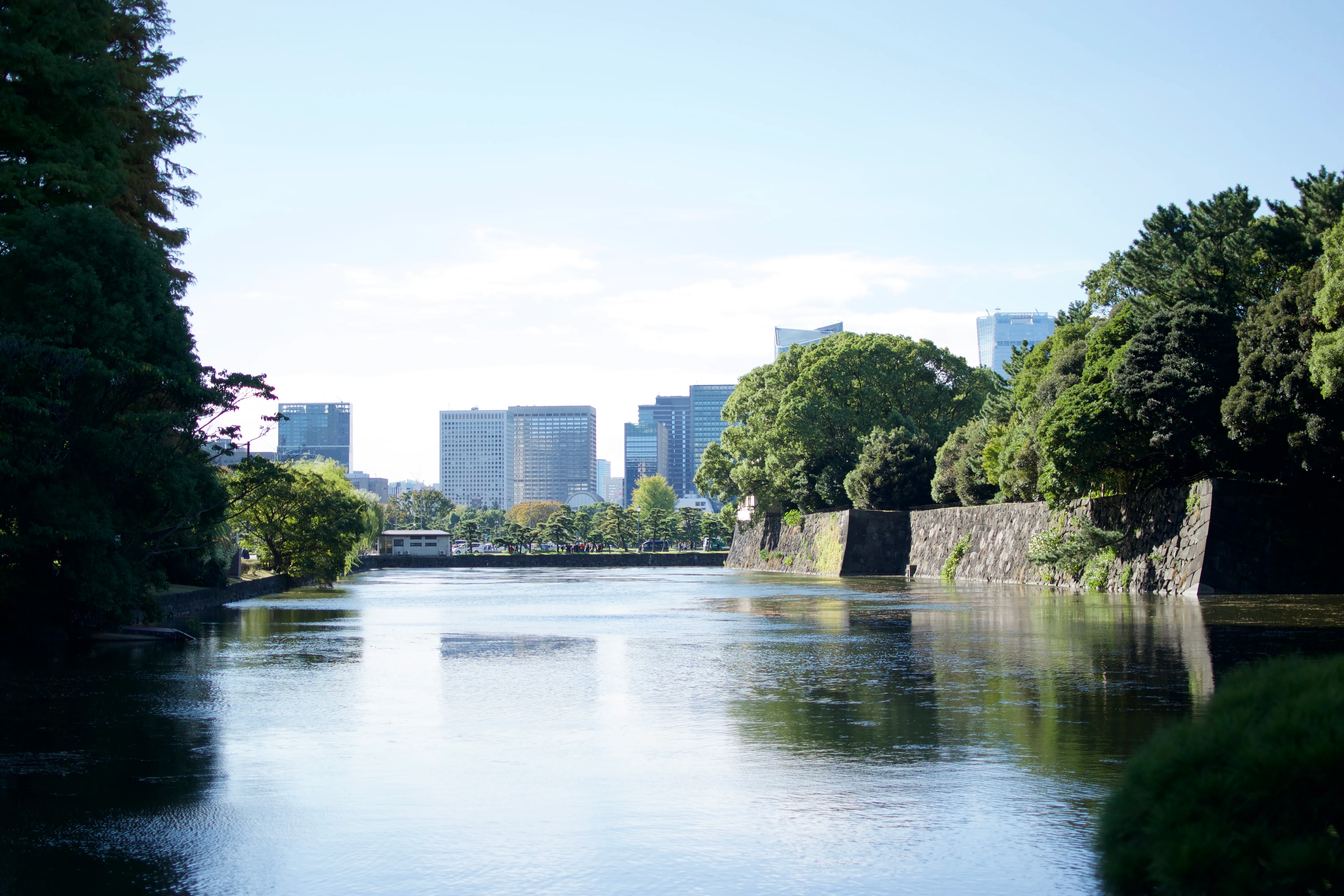 The moat outside the Japanese Imperial Palace, with skyscrapers in the distance and trees of the palace gardens on the right