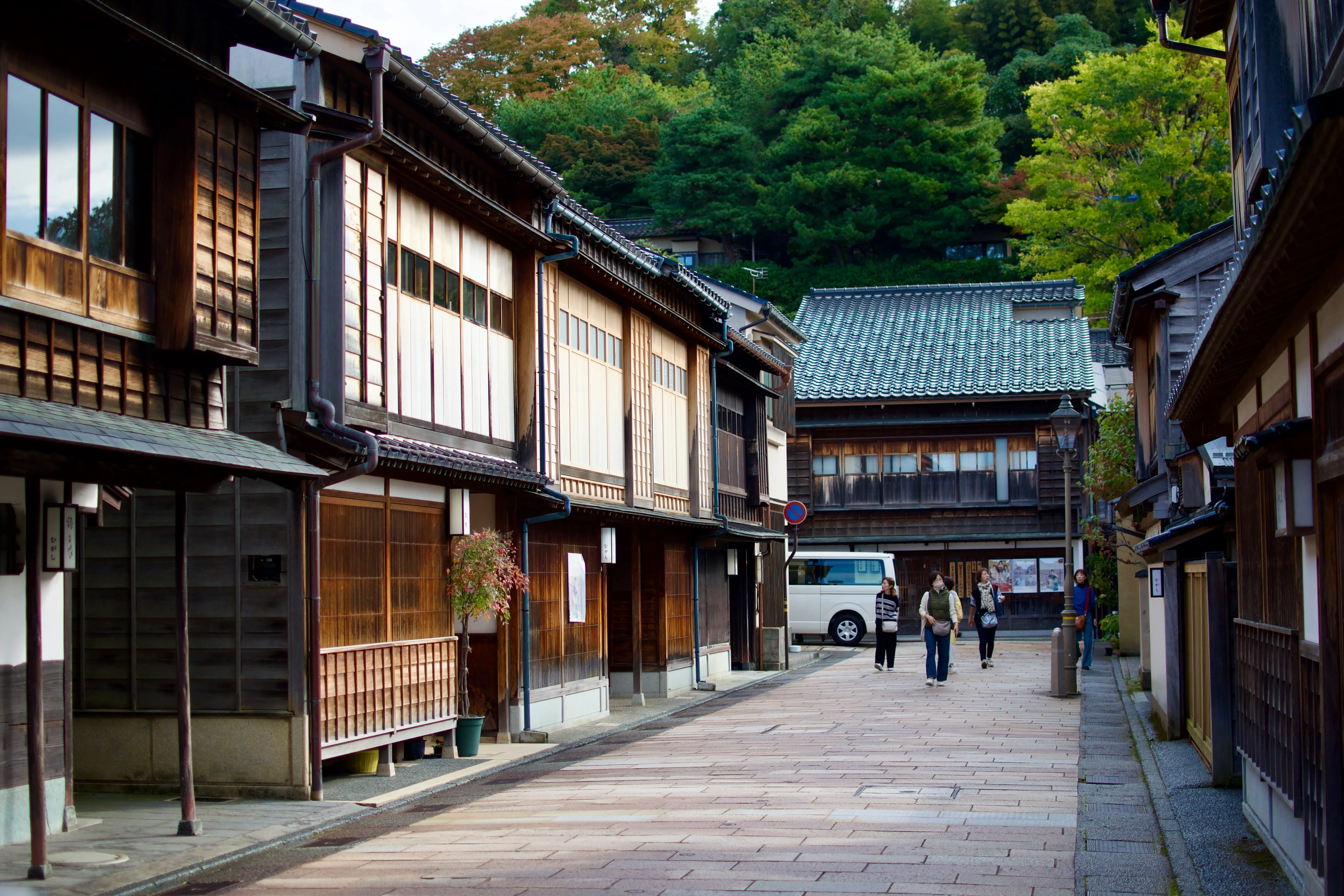 A quiet street scene in Kanazawa's historic Higashi Chaya district. There are wooden tea houses built close together with tiled roofs and shoji windows.