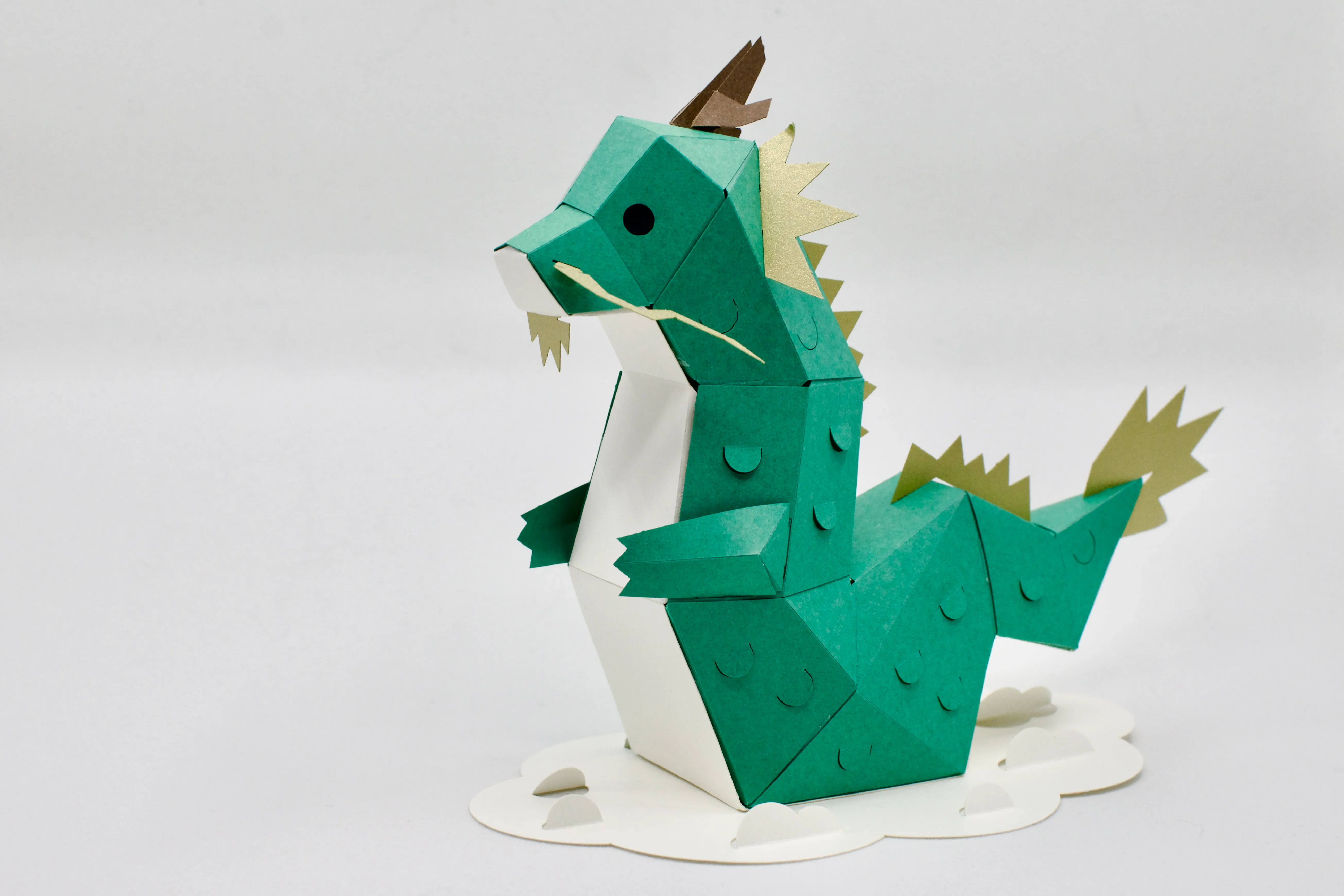 A papercraft Asian-style dragon with green body and gold trim