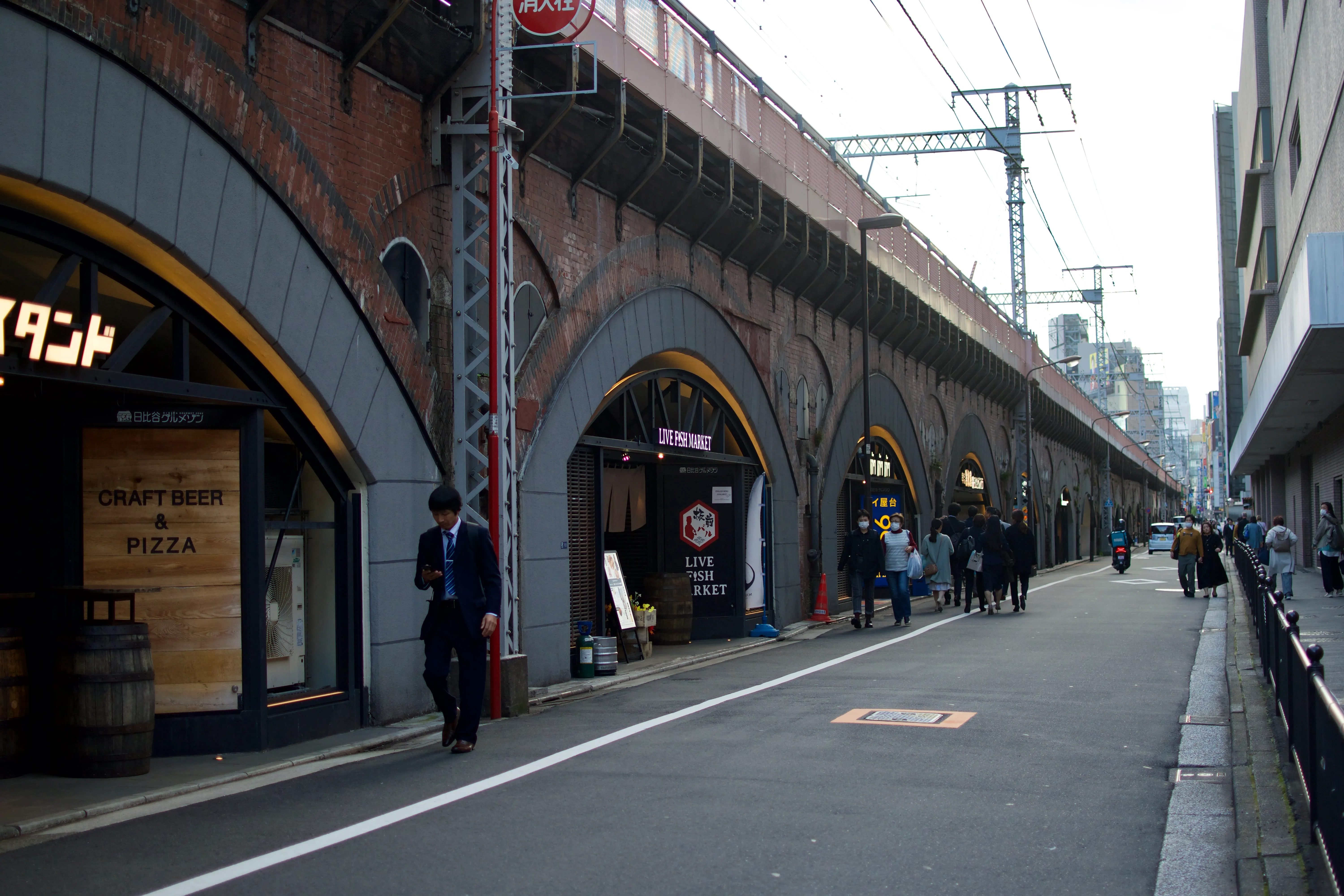 A fish market, a standing bar, and other shops built in the arches of an elevated train track.