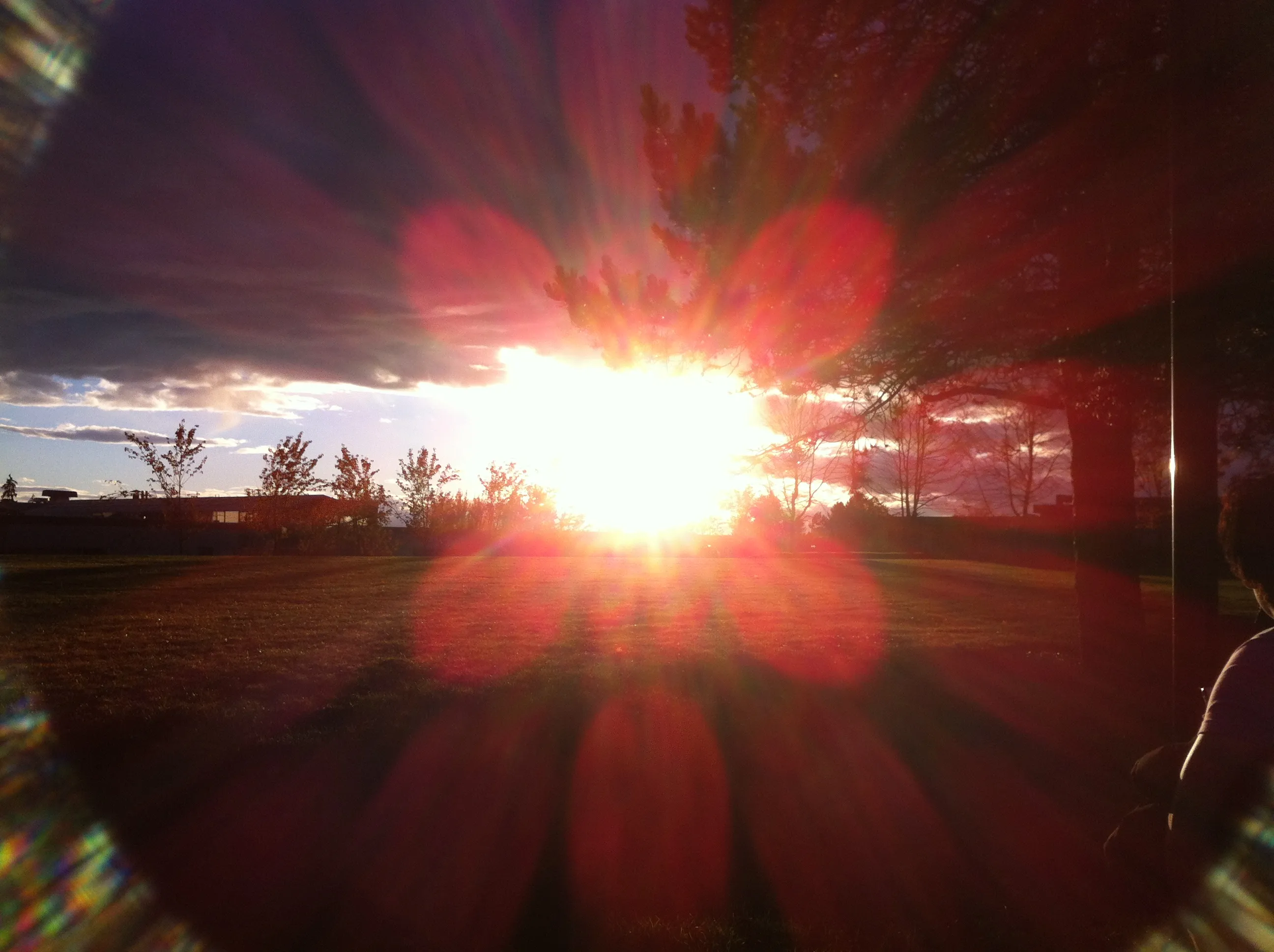 A lens flare emanating from the sun, centred in frame on the horizon. The flare appear as a grid of distorted red circles.