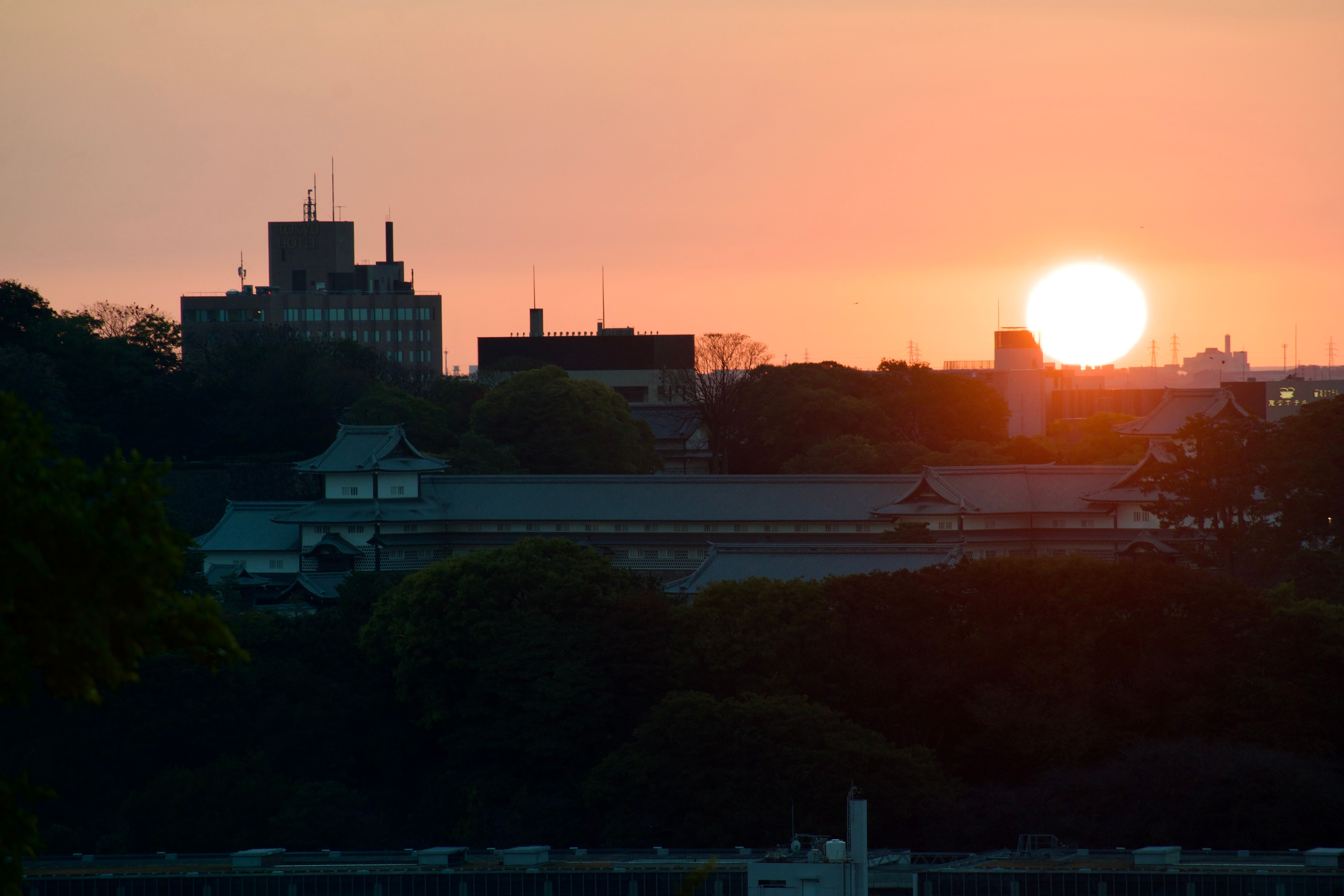 The sun sets over the city of Kanazawa, with Kanazawa Castle in the foreground in shadow.