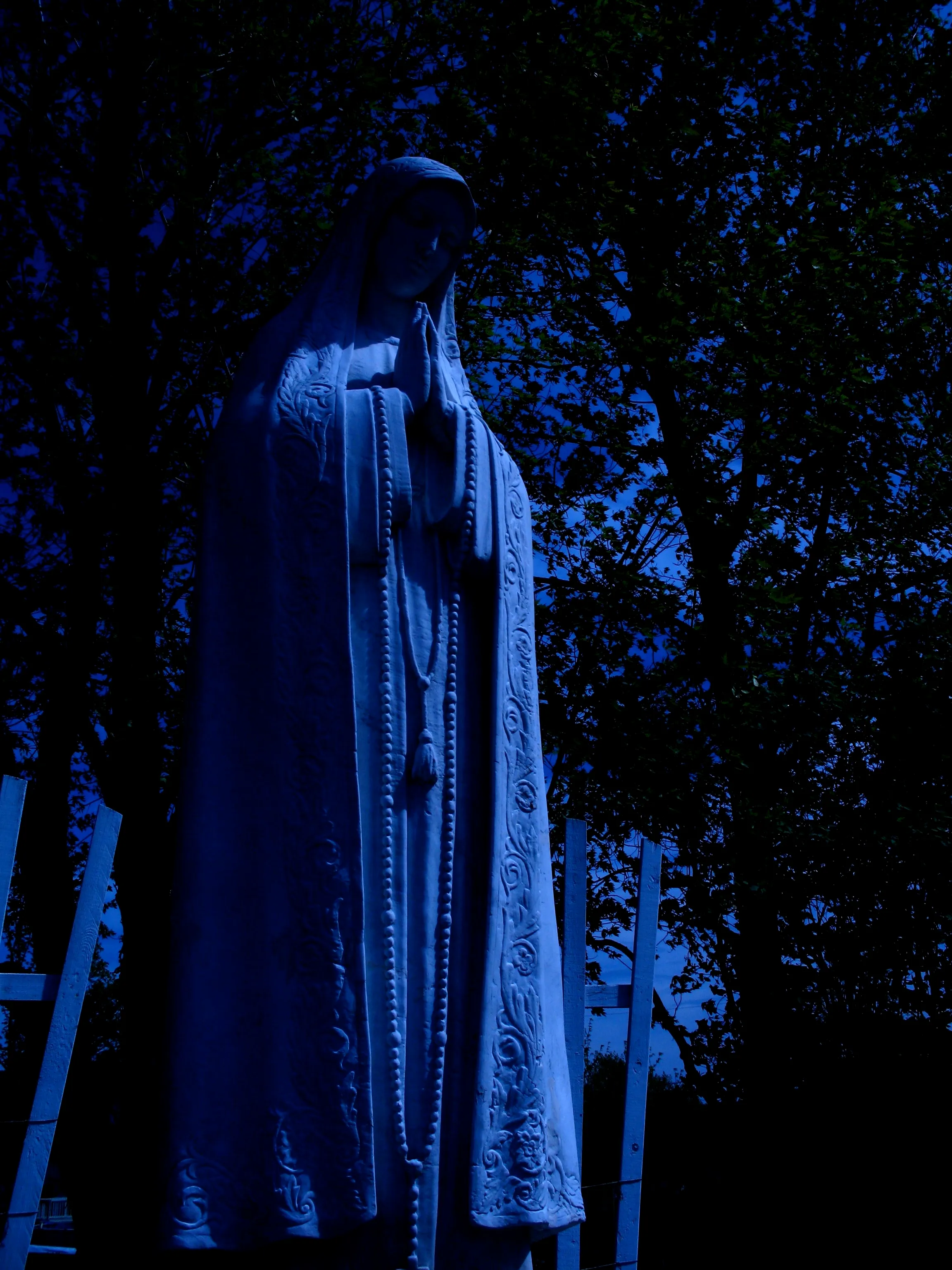 A statue of the Virgin Mary with an ominous blue colour-grade, as though it was a day-for-night shot in an old horror movie