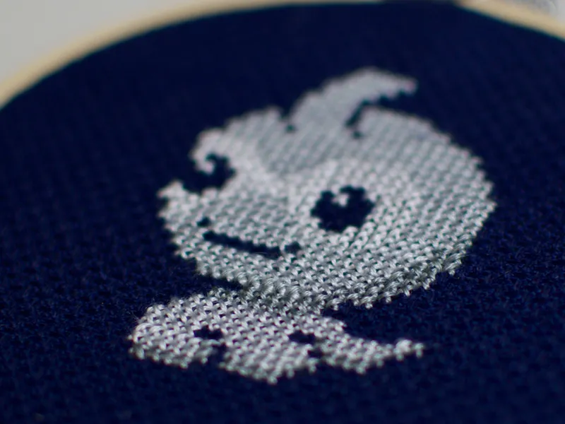A small cross-stitch of the weather Pokémon Castform against a navy background.
