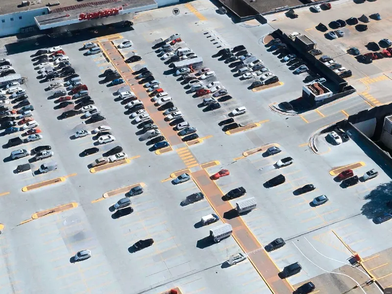 An aerial photo taken from Apple Maps of the entrance to a hypermarket. A parking lot takes up almost the entire image. The lot is about two-thirds full of about 200 cars.