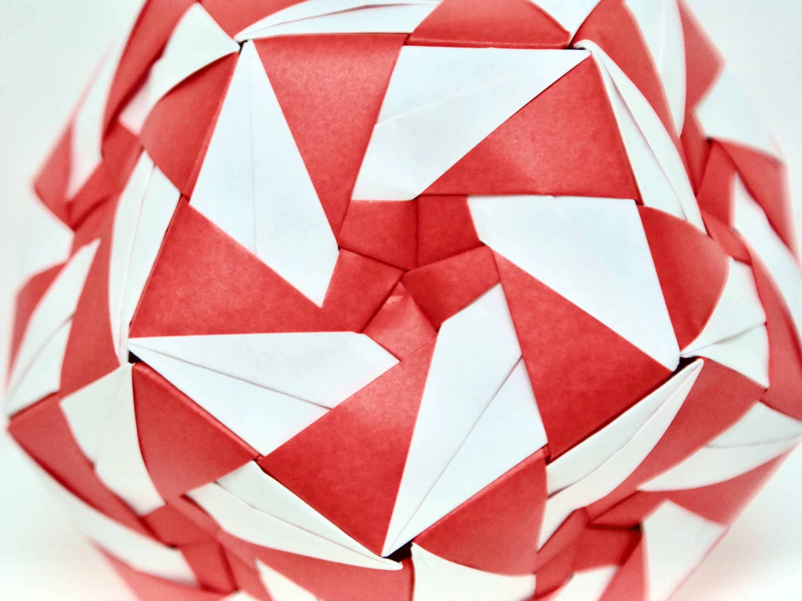 An origami dodecahedron with a red-and-white pinwheel pattern on each face.