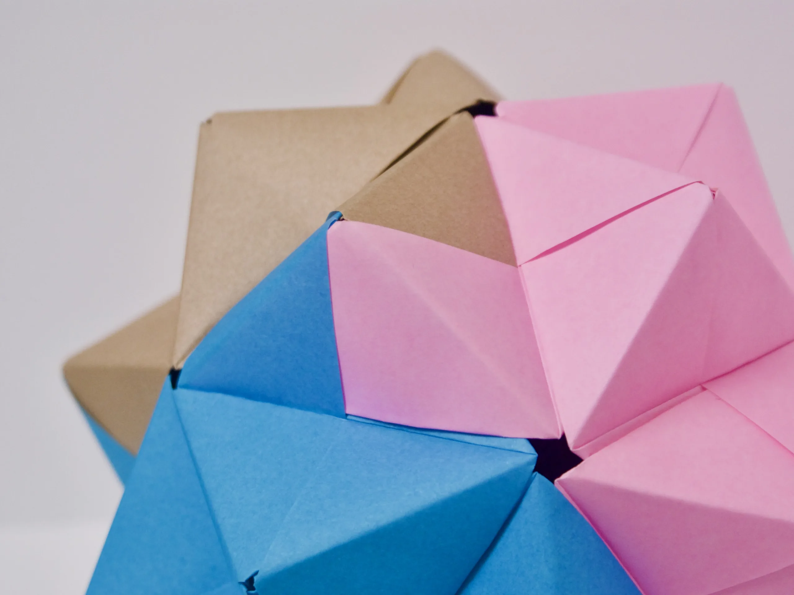 A spiky ball made from pink, brown, and blue origami paper.